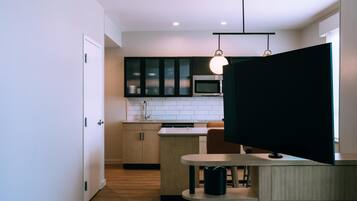 Una cocina moderna con microondas, armarios y una zona de comedor con mesa y sillas.