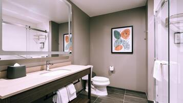 A modern bathroom with a large mirror, two sinks, a toilet, and a shower.