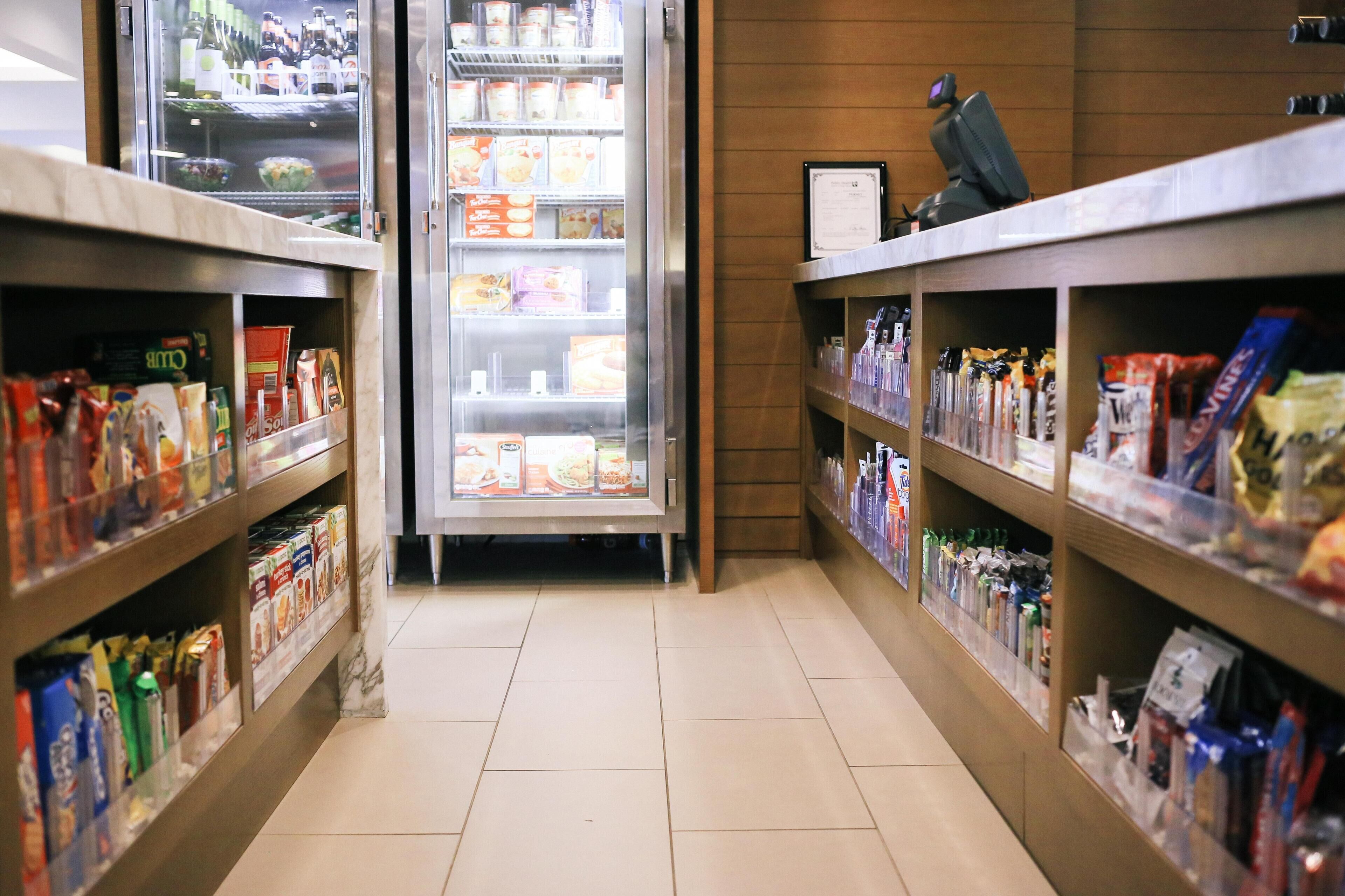 A grocery store aisle with refrigerated section and shelves stocked with snacks and beverages.