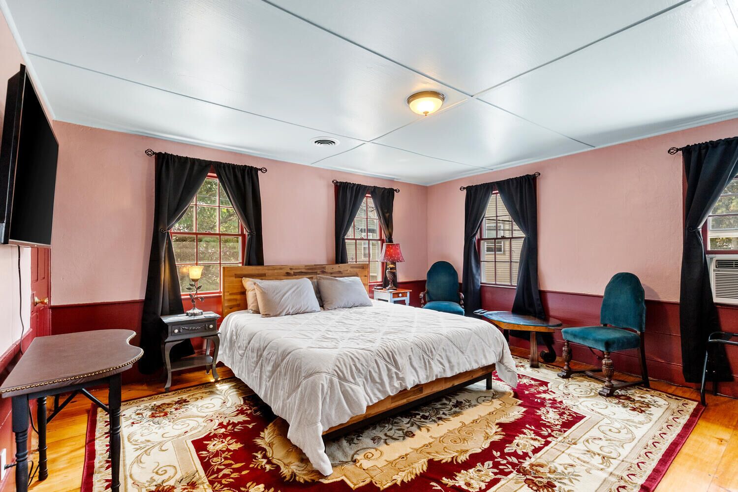 Een slaapkamer met een groot bed, twee stoelen, een bureau en een televisie.