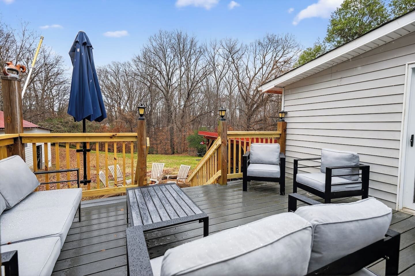 A wooden deck with outdoor furniture, including a sofa and chairs, and a small table.