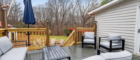 A wooden deck with outdoor furniture, including a sofa and chairs, and a small table.