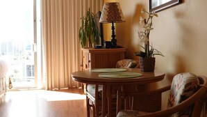 Un comedor con una mesa redonda de madera, dos sillas, una lámpara y una planta en maceta.