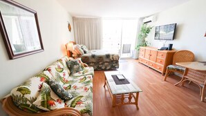 Una sala de estar con sofá, mesa de centro, televisor y aparador.