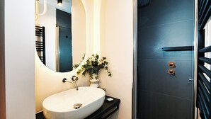 Ein modernes Badezimmer mit einem weißen Waschbecken, einem Spiegel und einer Duschkabine.