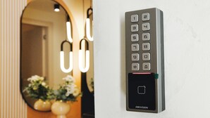 Ein an der Wand montiertes elektronisches Tastenfeld mit Zahlenschlüssel und kleinem Display, vermutlich zur Steuerung des Raumzugangs.