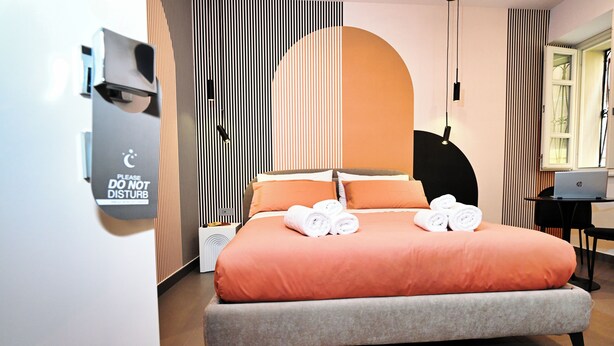 Ein modernes Schlafzimmer mit einem Bett, Kissen und einem Laptop auf einem Schreibtisch.