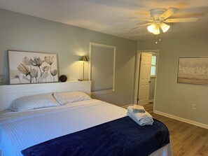 A bedroom with a bed, a ceiling fan, a wall-mounted lamp, and a door leading to another room. - 3-bedroom house in Heart of Cleveland. (Cleveland)