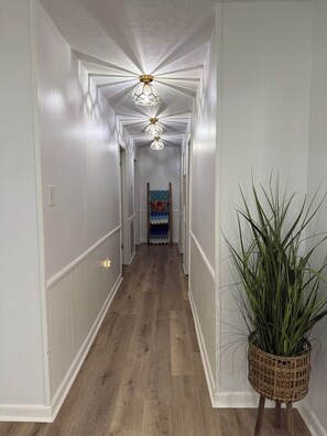A hallway with a wooden floor, white walls, and a ceiling fan. - 3-bedroom house in Heart of Cleveland. (Cleveland)