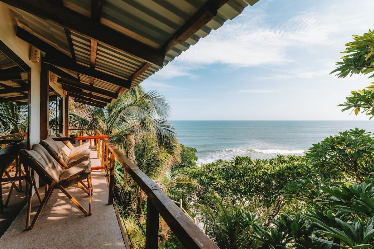A covered outdoor seating area with a view of the ocean.