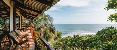 A covered outdoor seating area with a view of the ocean.
