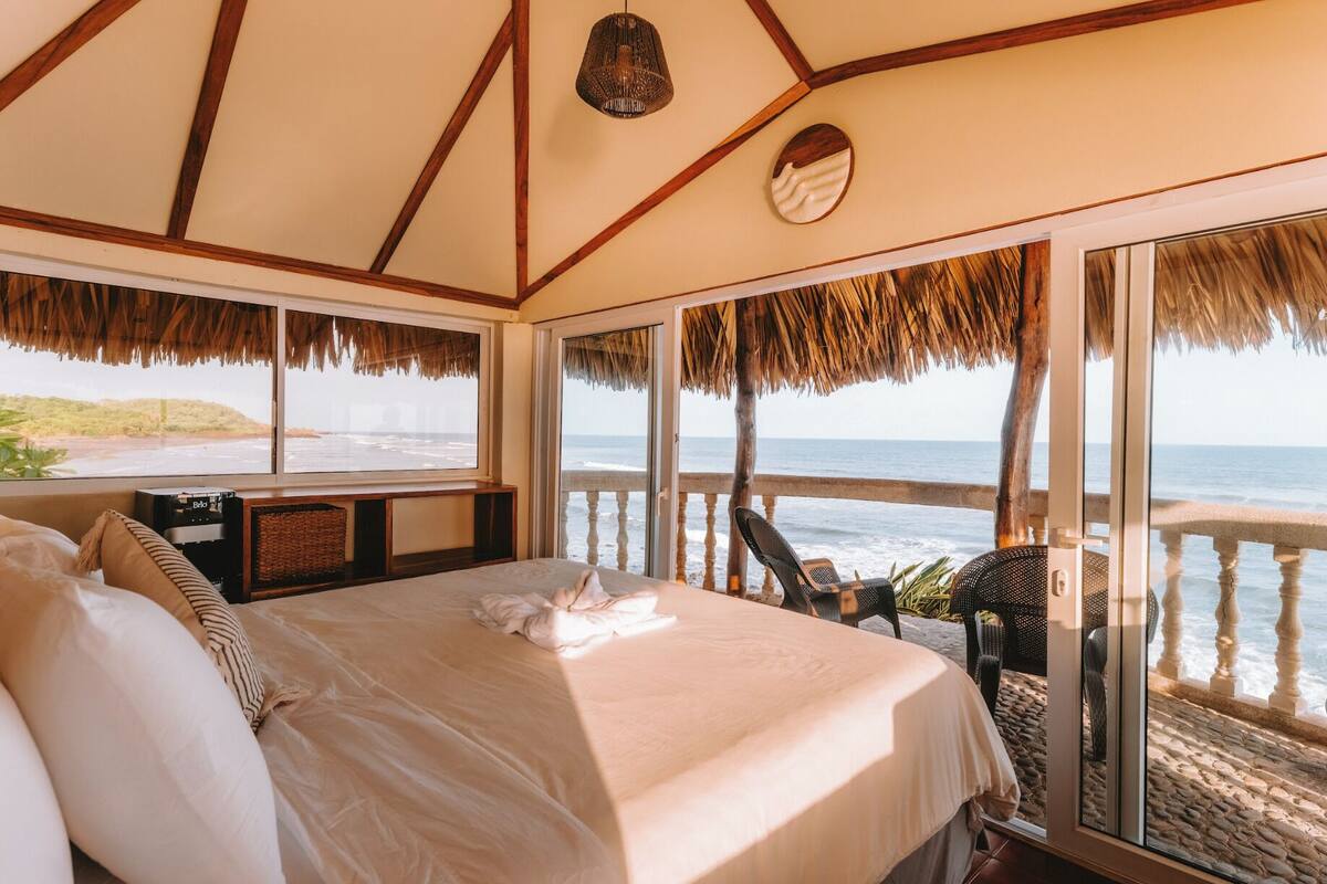 A bedroom with a large bed, a TV, and a view of the beach.