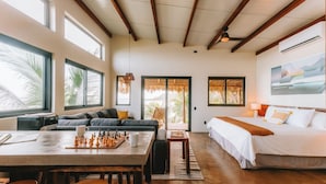 A spacious room with a large window, a cozy seating area, a bed, and a chessboard. - Punta Mango Villas (Jucuaran)