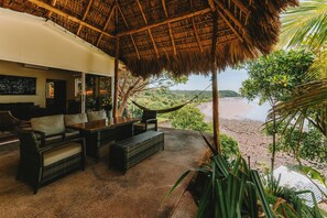 A thatched-roof outdoor seating area with wicker furniture overlooking a beach. - Punta Mango Villas (Jucuaran)
