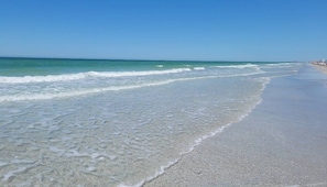 A beach with clear water, a sandy shore, and a distant shoreline with buildings. - ðChateau 5W - Gulf View condo - Great Discounts! (Belleair Beach)