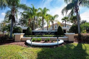 A landscaped entrance with a sign reading "Finca Key," surrounded by palm trees and a well-maintained lawn. - 4720 HH - Fiesta Key Grandeur (Kissimmee)