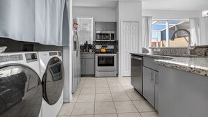 Una cucina moderna con lavatrice, forno a microonde, forno e un piano di lavoro in granito.