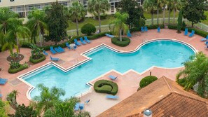 A swimming pool with a curved design, surrounded by lounge chairs and palm trees. - 4720 HH - Fiesta Key Grandeur (Kissimmee)