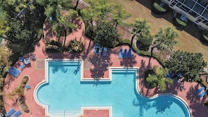 Vista aerea di una piscina con lettini e palme.