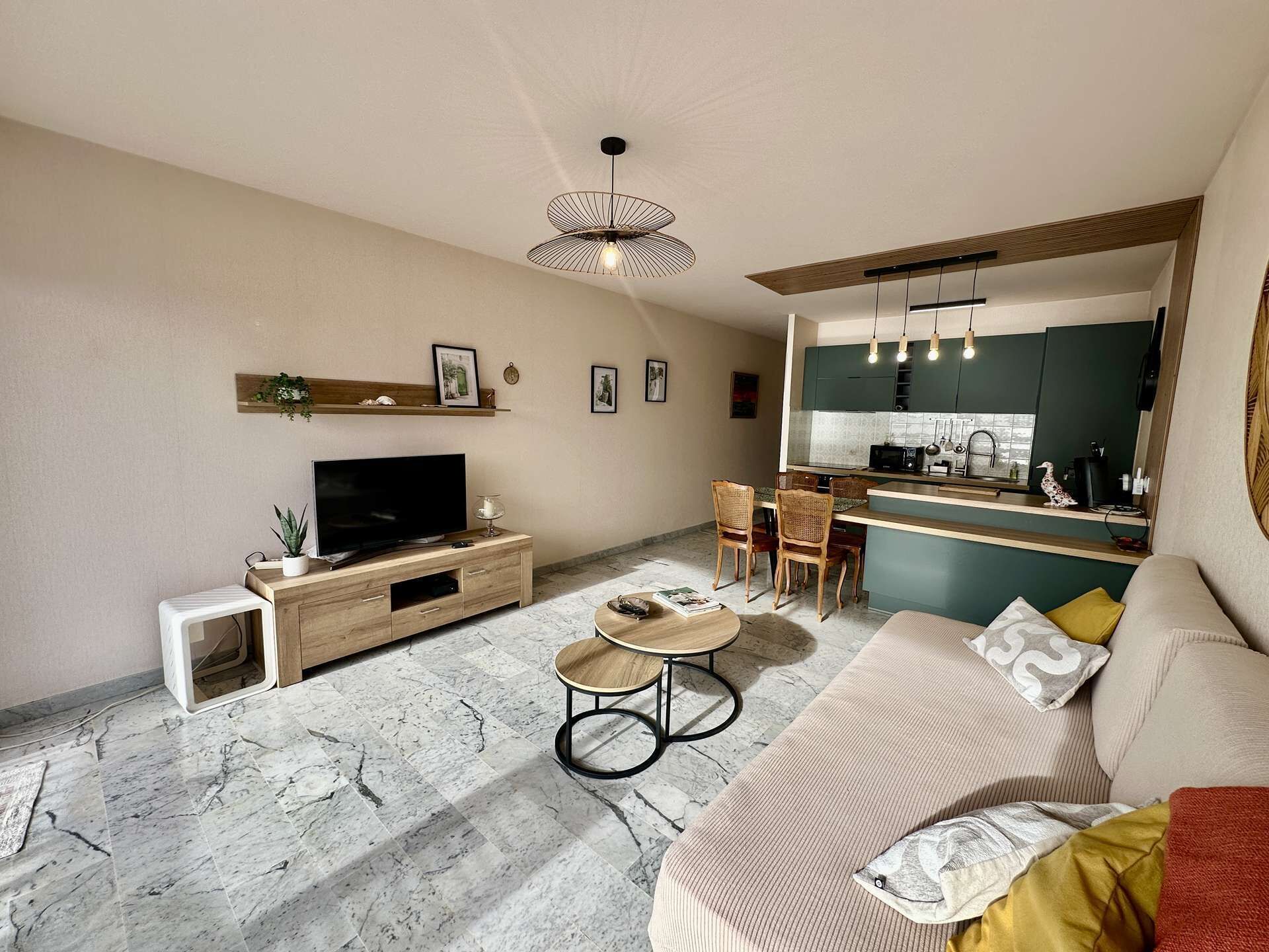 A modern living room with a flat-screen TV, a sofa, a coffee table, and a dining area with chairs.