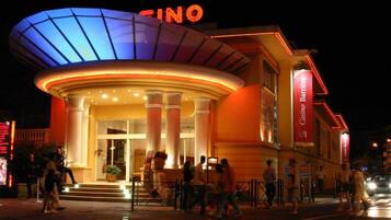 A hotel with a prominent 'CINQ' sign, a central entrance with columns, and a 'Cuisine Bar' sign.