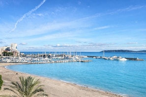 A marina with boats docked, a sandy beach, and a clear blue sky. - SEAFRONT APARTMENT FOR 4 PEOPLE – TOWN CENTER (STE MAXIME)