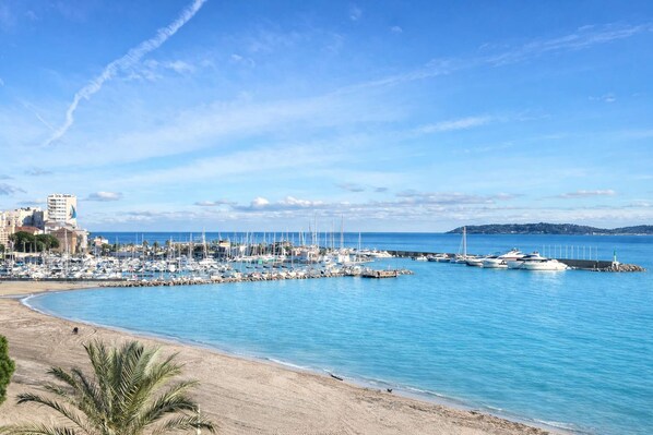 A marina with boats docked, a sandy beach, and a clear blue sky. - SEAFRONT APARTMENT FOR 4 PEOPLE – TOWN CENTER (STE MAXIME)