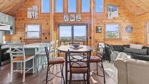 A cozy cabin with a wooden interior, a dining area with a round table, and a sofa in the living room. - North Star Trailside • Hiking • Moose Pond (Bridgton)