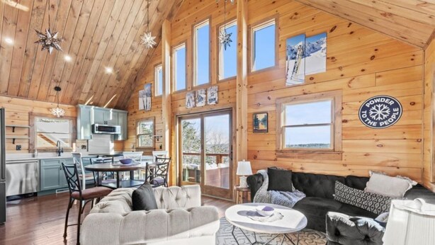 A log cabin interior with a dining area, kitchen, and living room. - North Star Trailside • Hiking • Moose Pond (Bridgton)