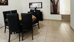 A dining area with a ceiling fan, a dining table with chairs, a mirror, and a potted plant.