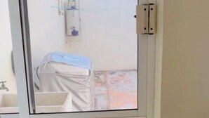 A room with a window, a small table, and a covered object.