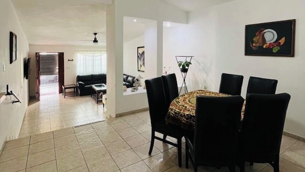 A spacious living area with a dining table, chairs, and a ceiling fan.