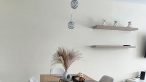 A modern dining area with a wooden table, grey upholstered chairs, a vase with dried plants, and decorative hanging lights. - Modern 2BR Furnished Home near DIX30 & Downtown Montreal— Monthly Stays Welcome (Longueuil)
