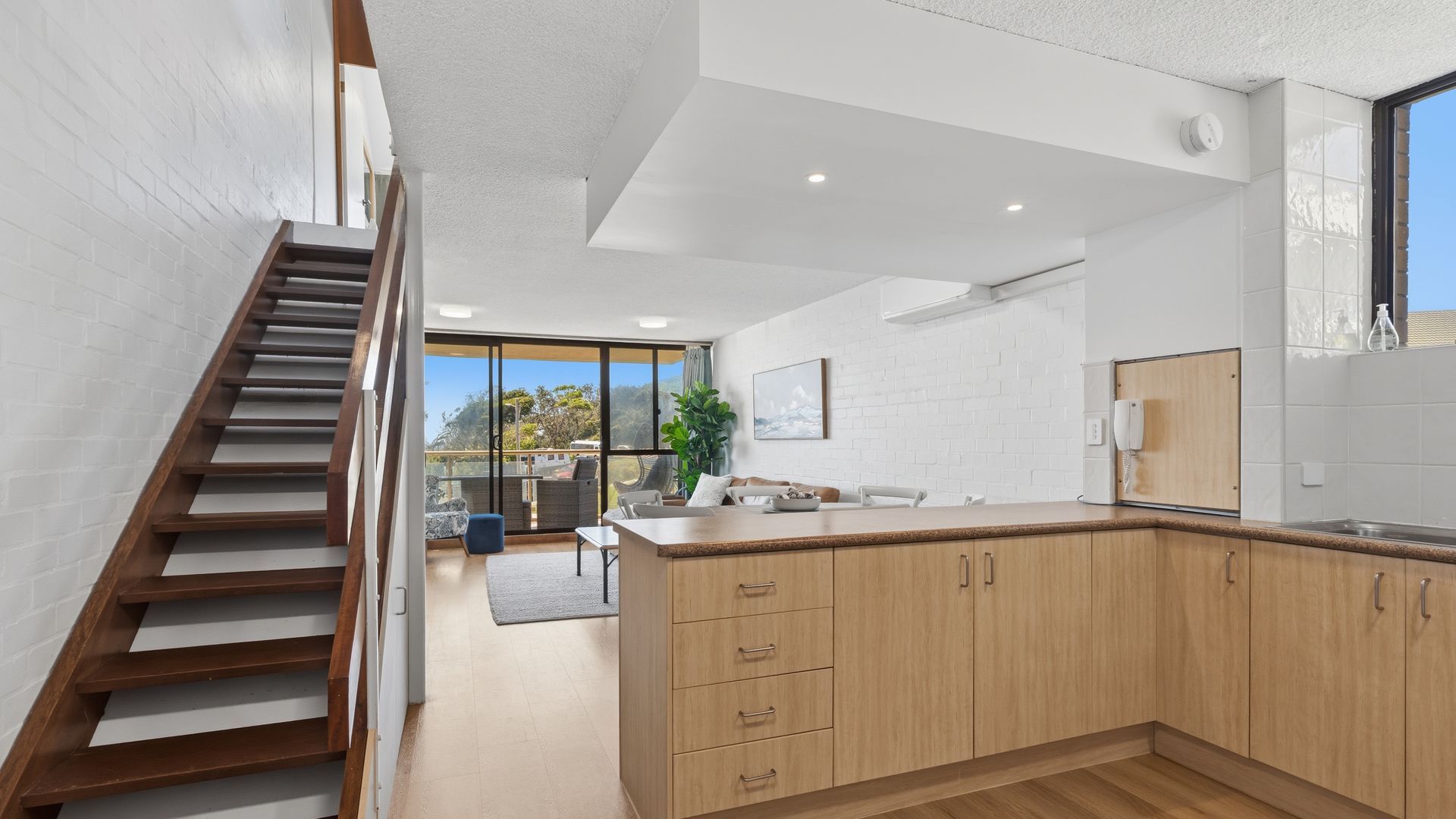 A modern kitchen with wooden cabinets, a built-in oven, and a large window.