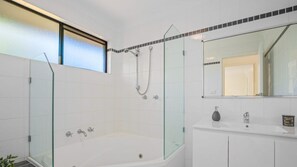 A modern bathroom with a glass-enclosed shower, a freestanding bathtub, and a white vanity with a mirror. - Tranquility At Lighthouse Beach (Port Macquarie)