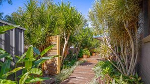 Un jardin avec un sentier en bois menant à une maison.