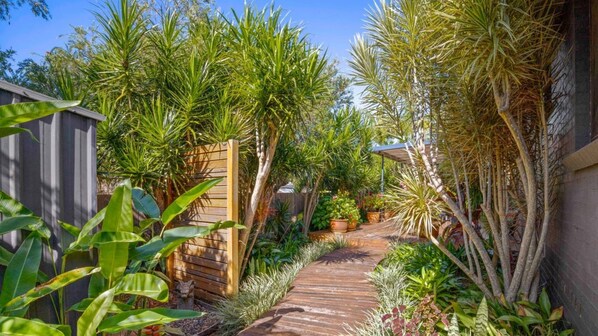 A garden with a wooden pathway leading to a house.