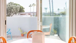 A balcony with a table, chairs, and potted plants. - Hip 3-bedroom House with AC/Pool/Hot Tub in Vibrant Palm Springs (Palm Springs)