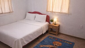 Ein Schlafzimmer mit einem Bett, einem Nachttisch mit Lampe und einem blauen Teppich mit Schrift.