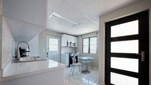 A modern kitchen with white cabinets, a stainless steel sink, and a dining area with a glass table and chairs. - 2-bedroom apartment in serene Hato Rey close to El Coliseum (San Juan)