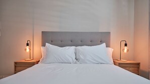 A neatly made bed with white linens, flanked by two bedside tables with modern lamps. - 2-bedroom apartment in serene Hato Rey close to El Coliseum (San Juan)