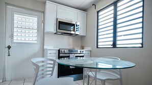 A modern kitchen with white cabinetry, a glass-top dining table, and a built-in microwave. - 2-bedroom apartment in serene Hato Rey close to El Coliseum (San Juan)
