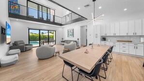 Interior moderno com área de jantar, cozinha e varanda com vista para a piscina.