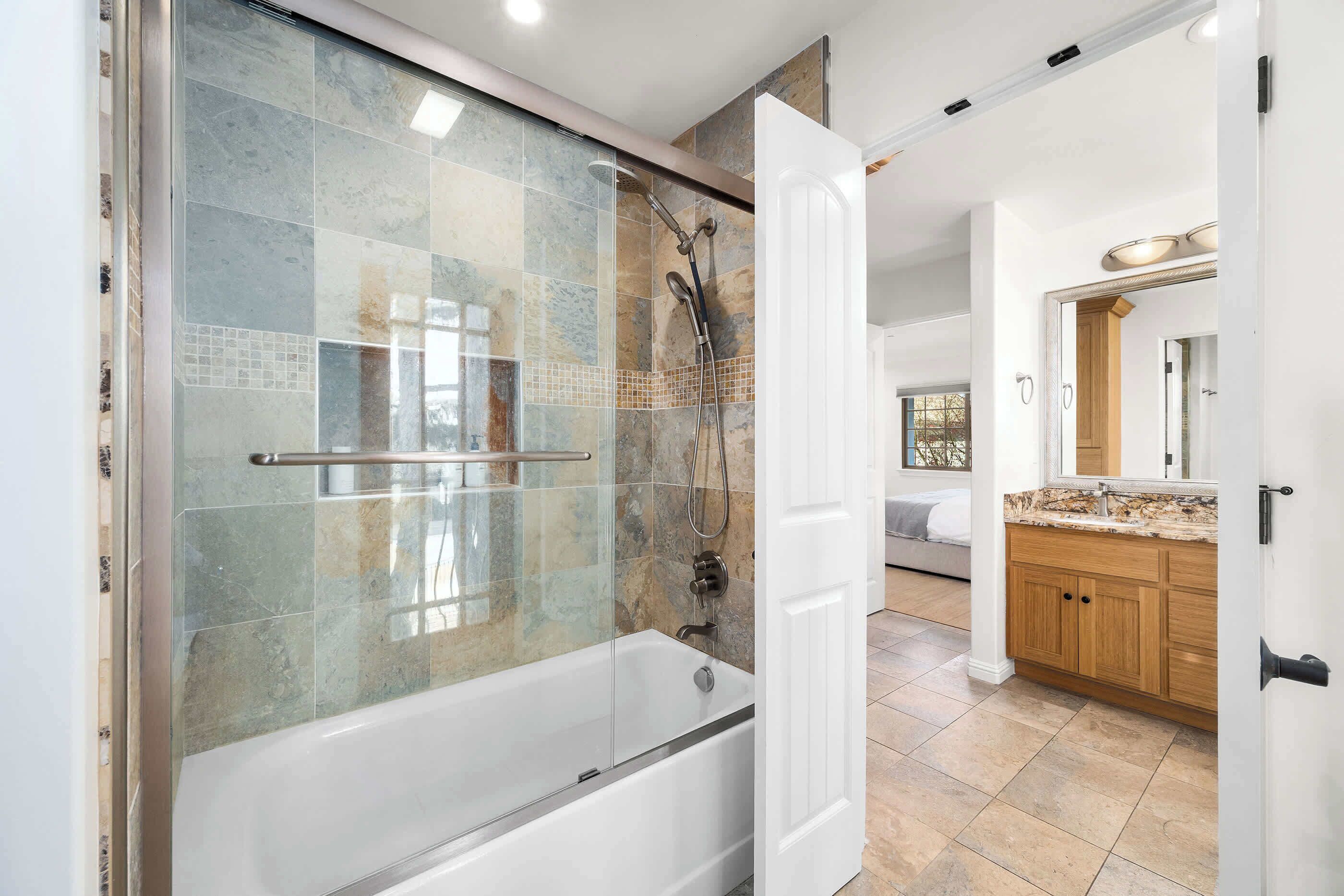 A modern bathroom with a glass-enclosed shower, a bathtub, and a wooden vanity with a sink.