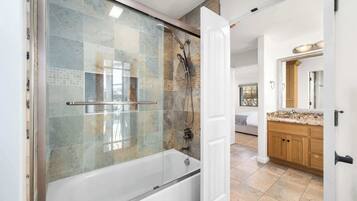 A modern bathroom with a glass-enclosed shower, a bathtub, and a wooden vanity with a sink.