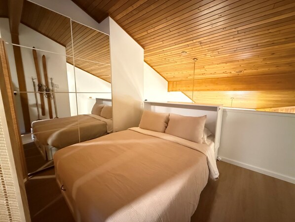 A bedroom with two beds, wooden ceiling, and a large window. - Summit View Collection |Ski-In ·Hot Tub ·Sleeps 14 (Kimberley)