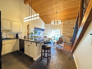 Una cucina moderna con mobili bianchi, un'isola centrale e un camino in pietra.