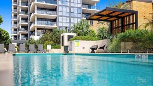 A swimming pool with lounge chairs and a view of modern buildings in the background. - Luxury Beachfront Burleigh Heads (Burleigh Heads)