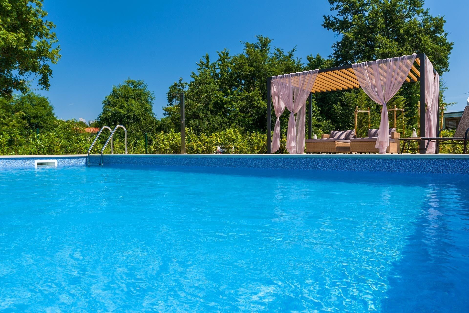Piscina azul cristalina con muelle de madera y zona de estar cubierta.