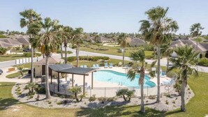 Zona residencial con piscina rodeada de palmeras y un pabellón.